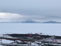 McMurdo sound. there is a tiny shack on the ice. To the right of it is a black dot thing. its a seal